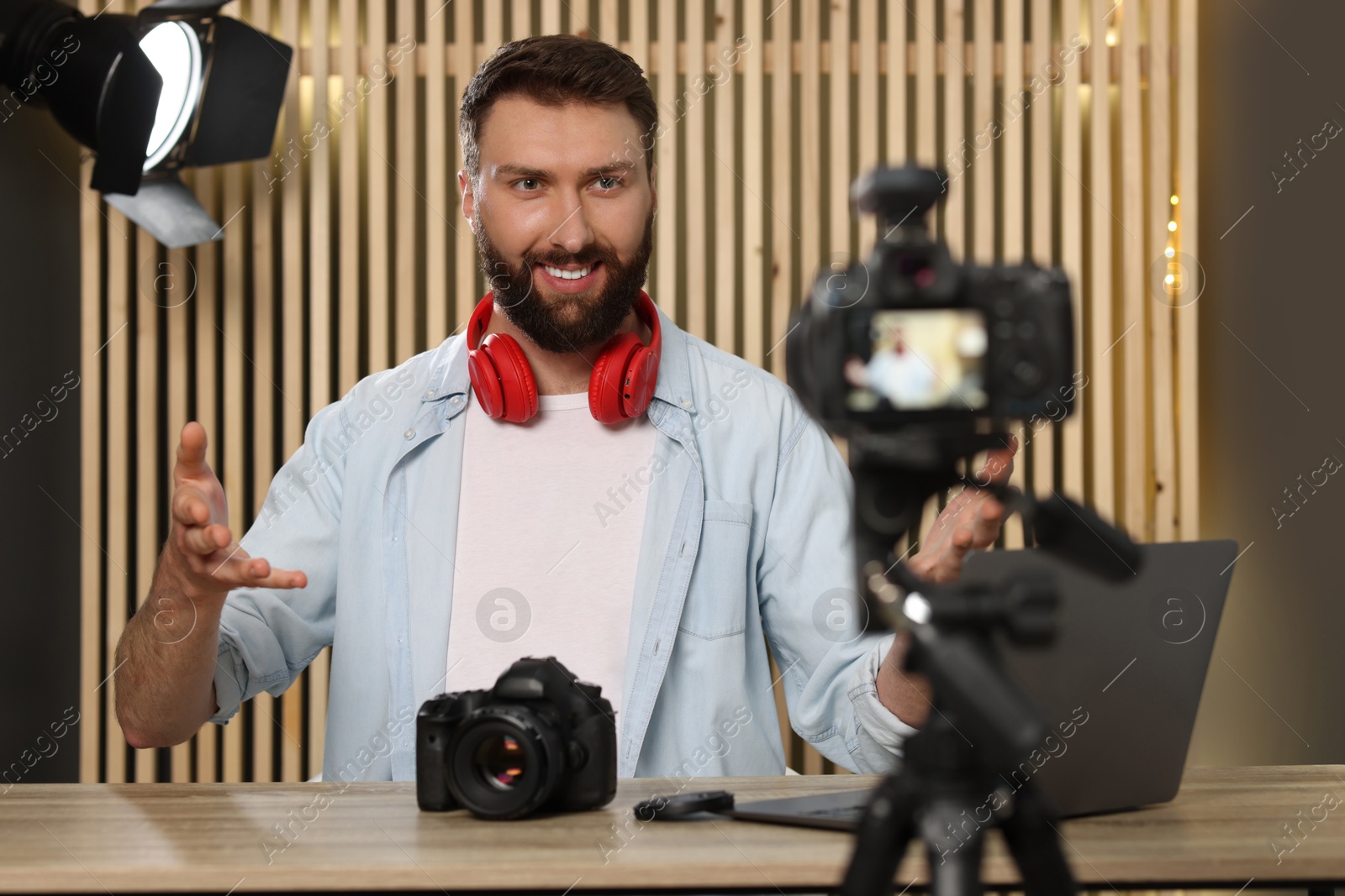 Photo of Smiling technology blogger with camera recording video review at home