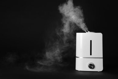 Photo of Modern air humidifier on black background. Space for text