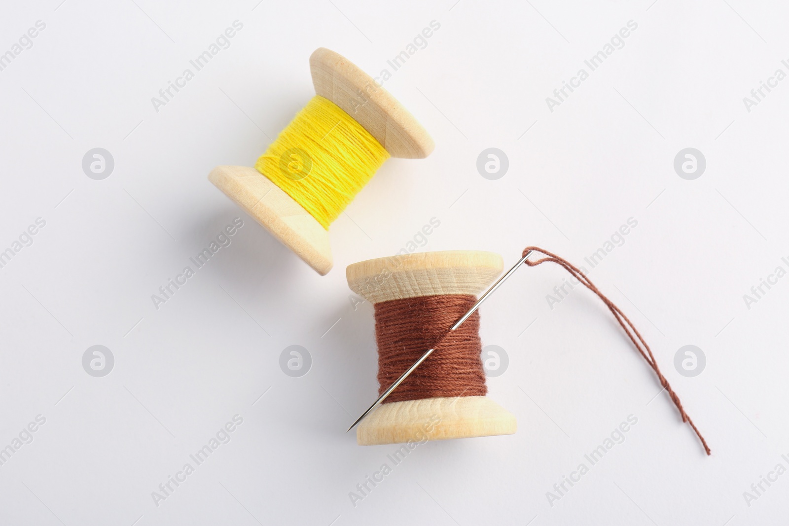 Photo of Colorful sewing threads with needle on white background, top view