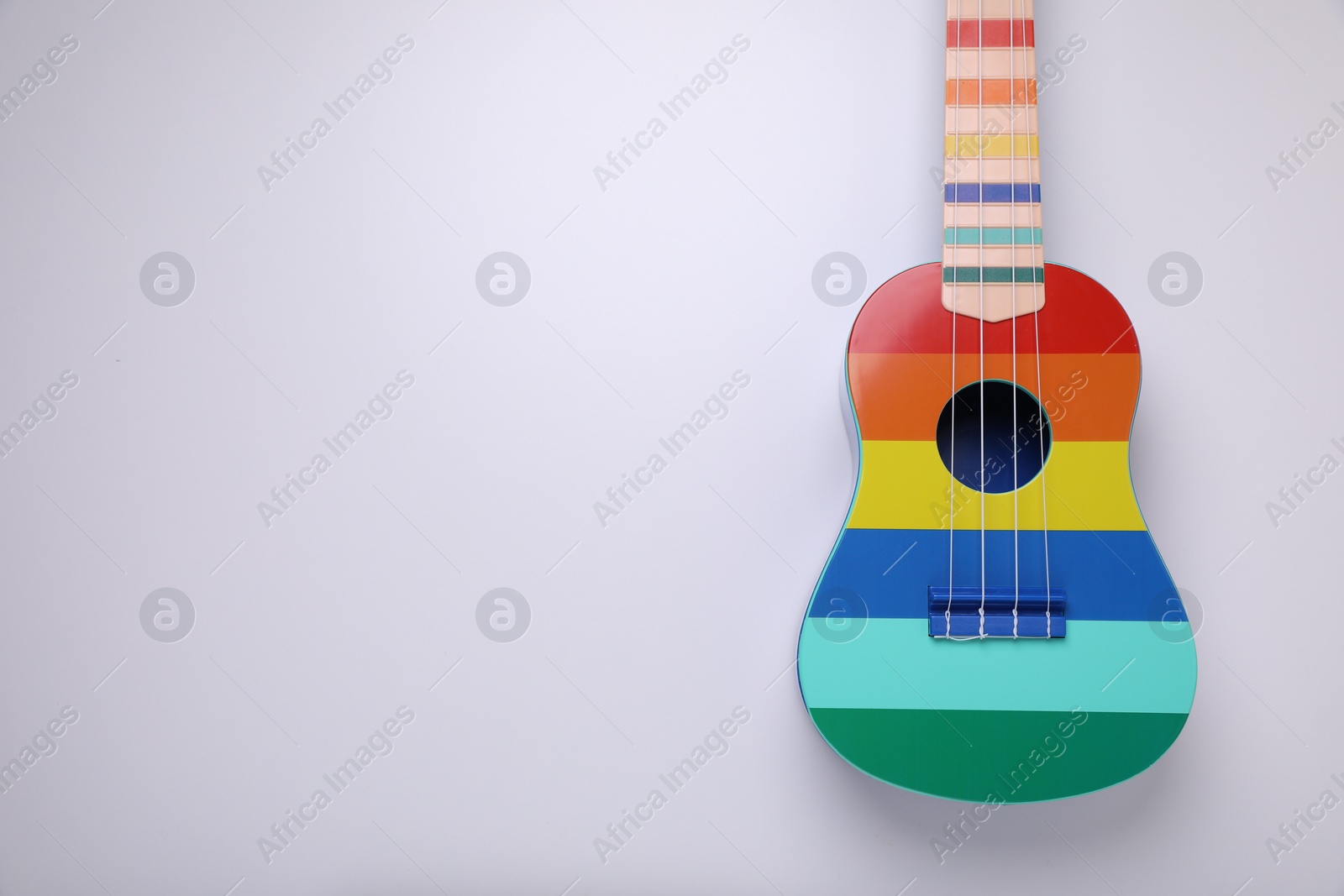 Photo of Colorful ukulele on white background, top view and space for text. String musical instrument