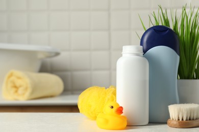Photo of Baby cosmetic products, bath duck, brush and sponge on white table. Space for text