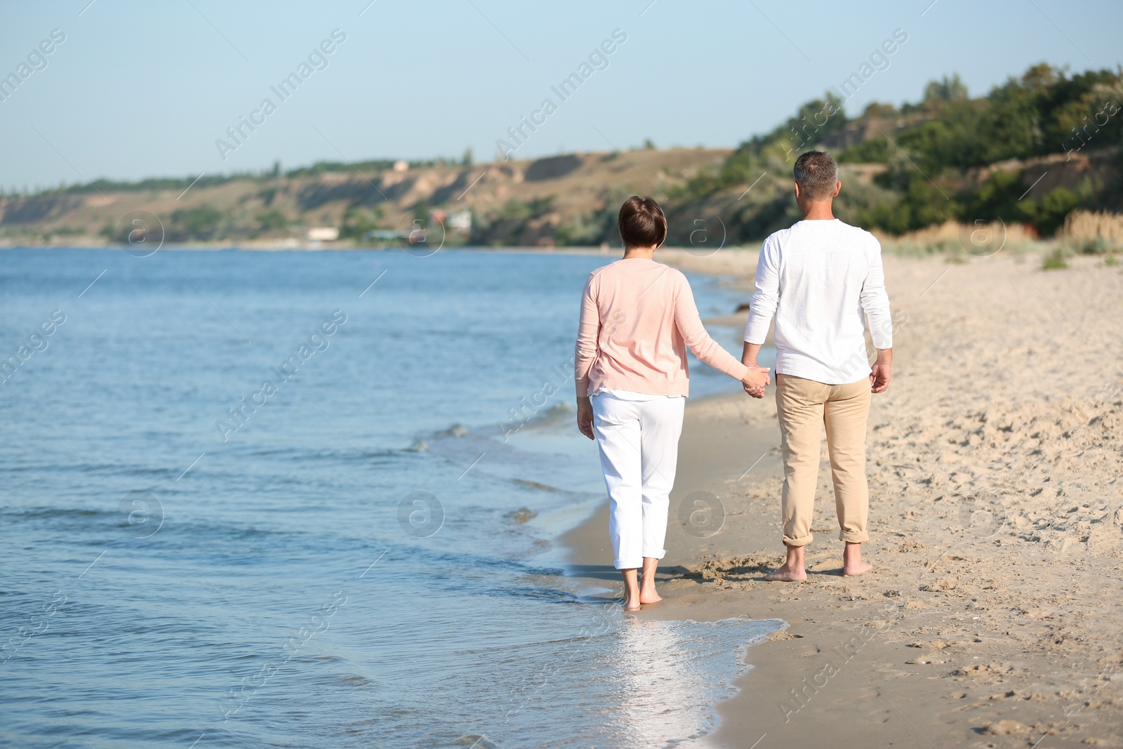 Photo of Happy mature couple walking at beach on sunny day