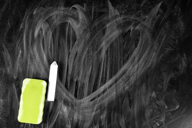 Dirty chalkboard with duster, closeup. School equipment