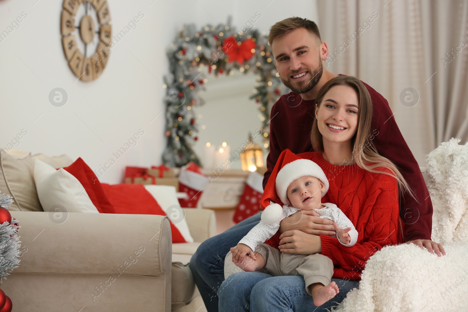 Photo of Happy family with cute baby in room decorated for Christmas holiday