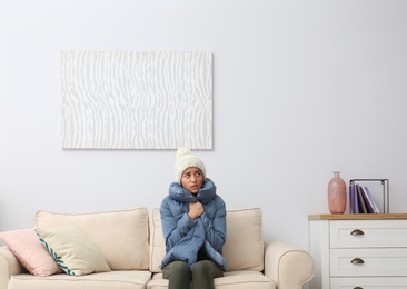 Young woman freezing under air conditioner at home