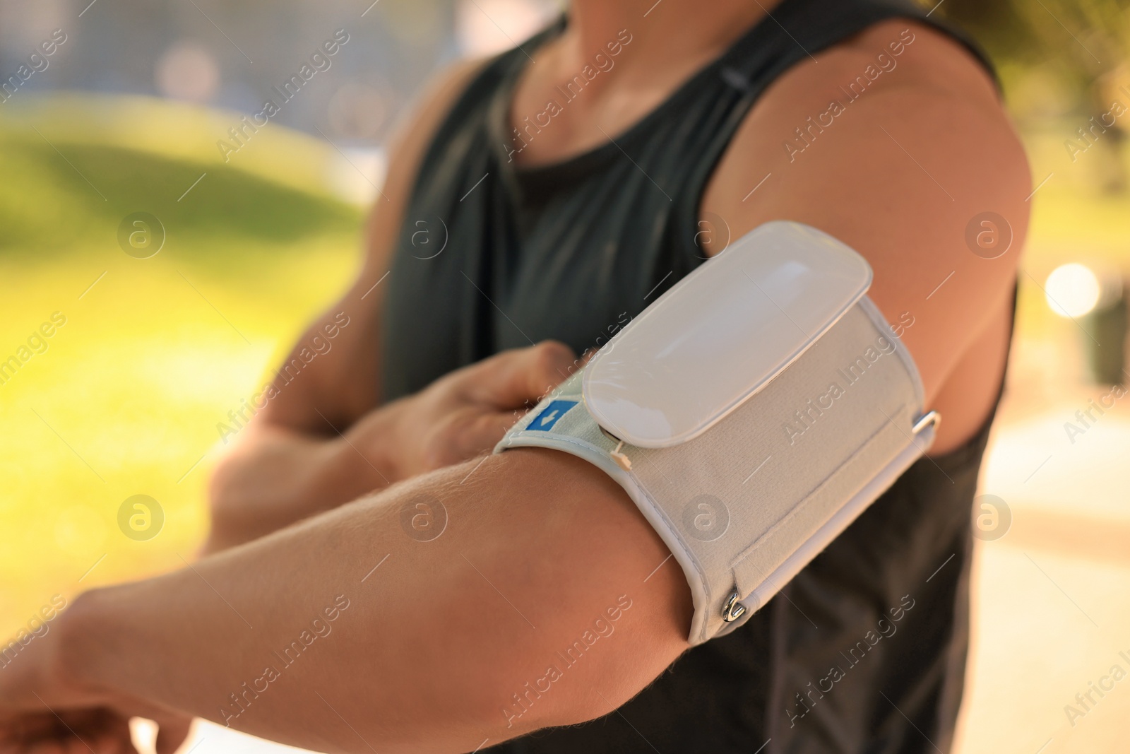 Photo of Man checking blood pressure with modern monitor after training on sunny day, closeup