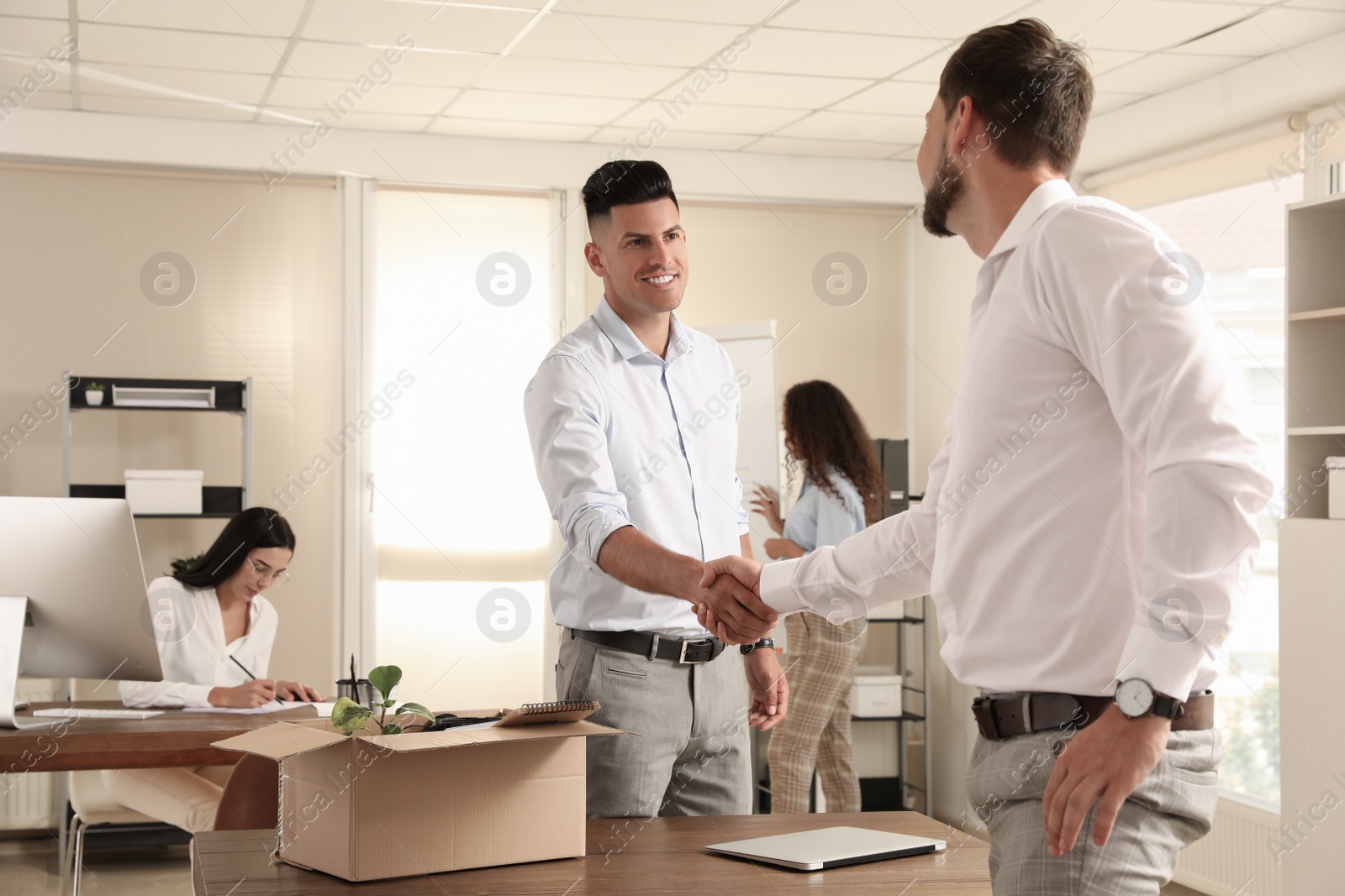 Photo of Employee shaking hand with new coworker in office