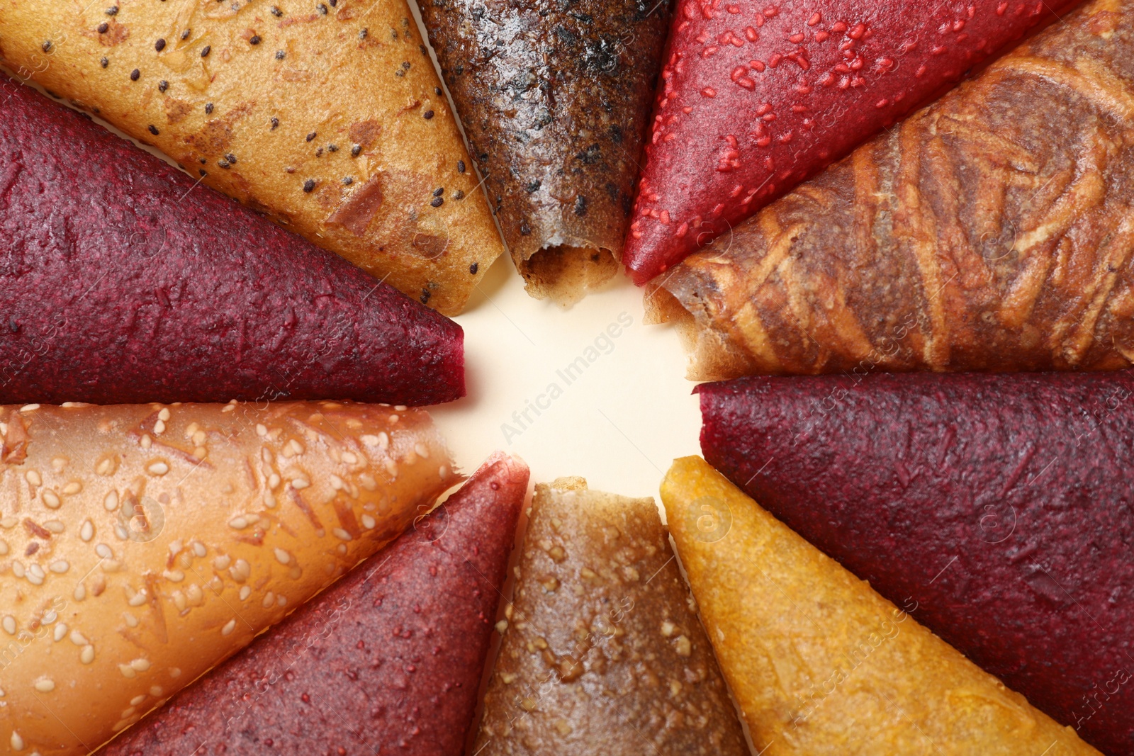 Photo of Delicious fruit leather rolls on beige background, closeup