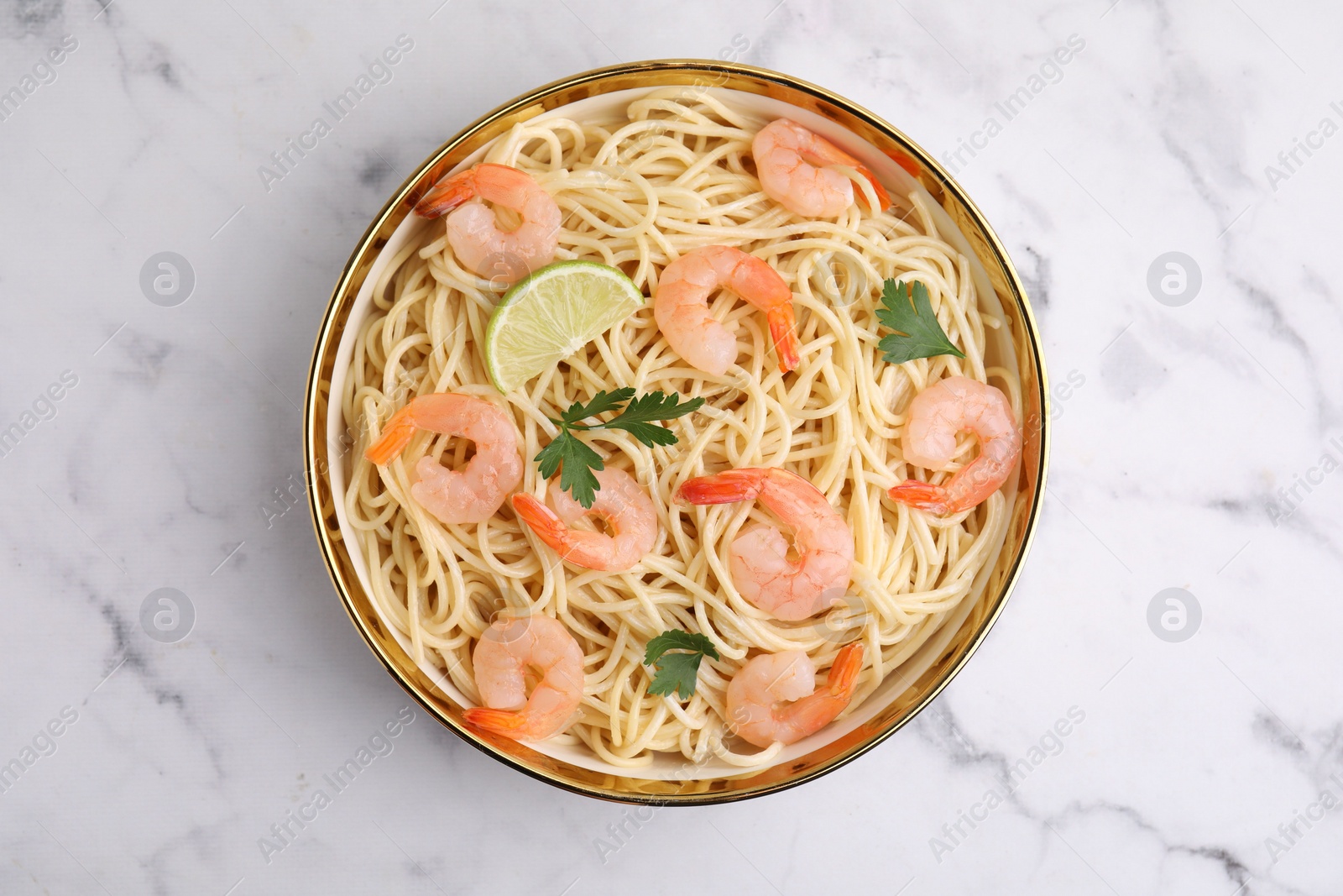 Photo of Tasty spaghetti with shrimps, lime and parsley in bowl on white marble table, top view