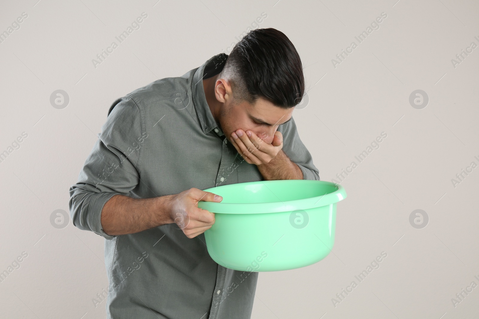 Photo of Man with basin suffering from nausea on beige background. Food poisoning