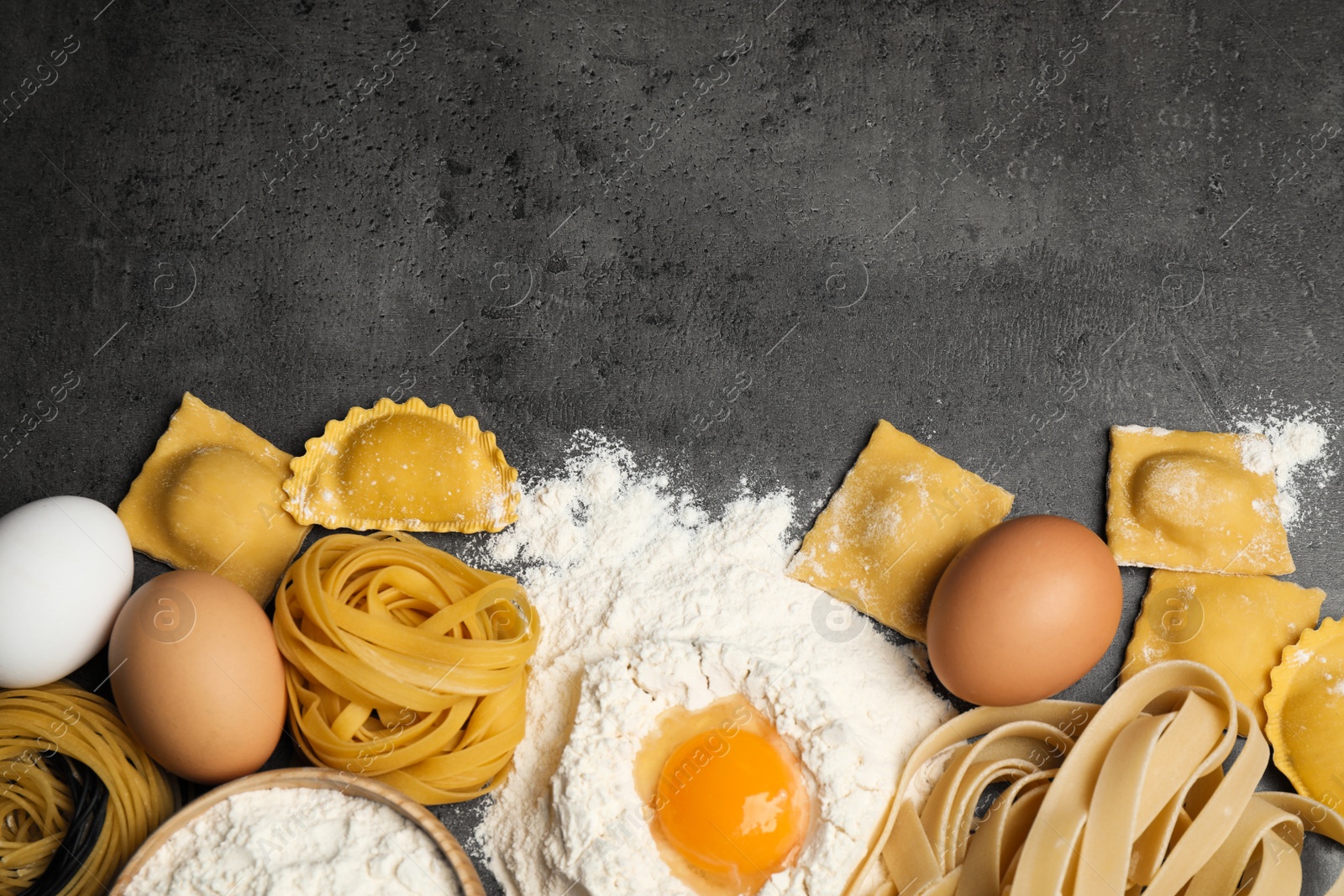 Photo of Flat lay composition with different types of pasta on grey table. Space for text