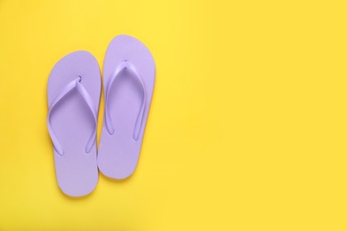 Photo of Stylish violet flip flops on yellow background, top view. Space for text