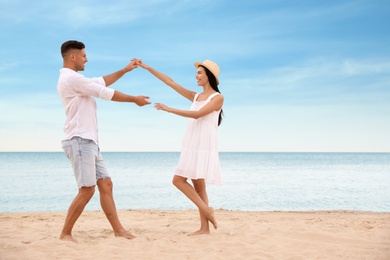Lovely couple dancing on beach near sea