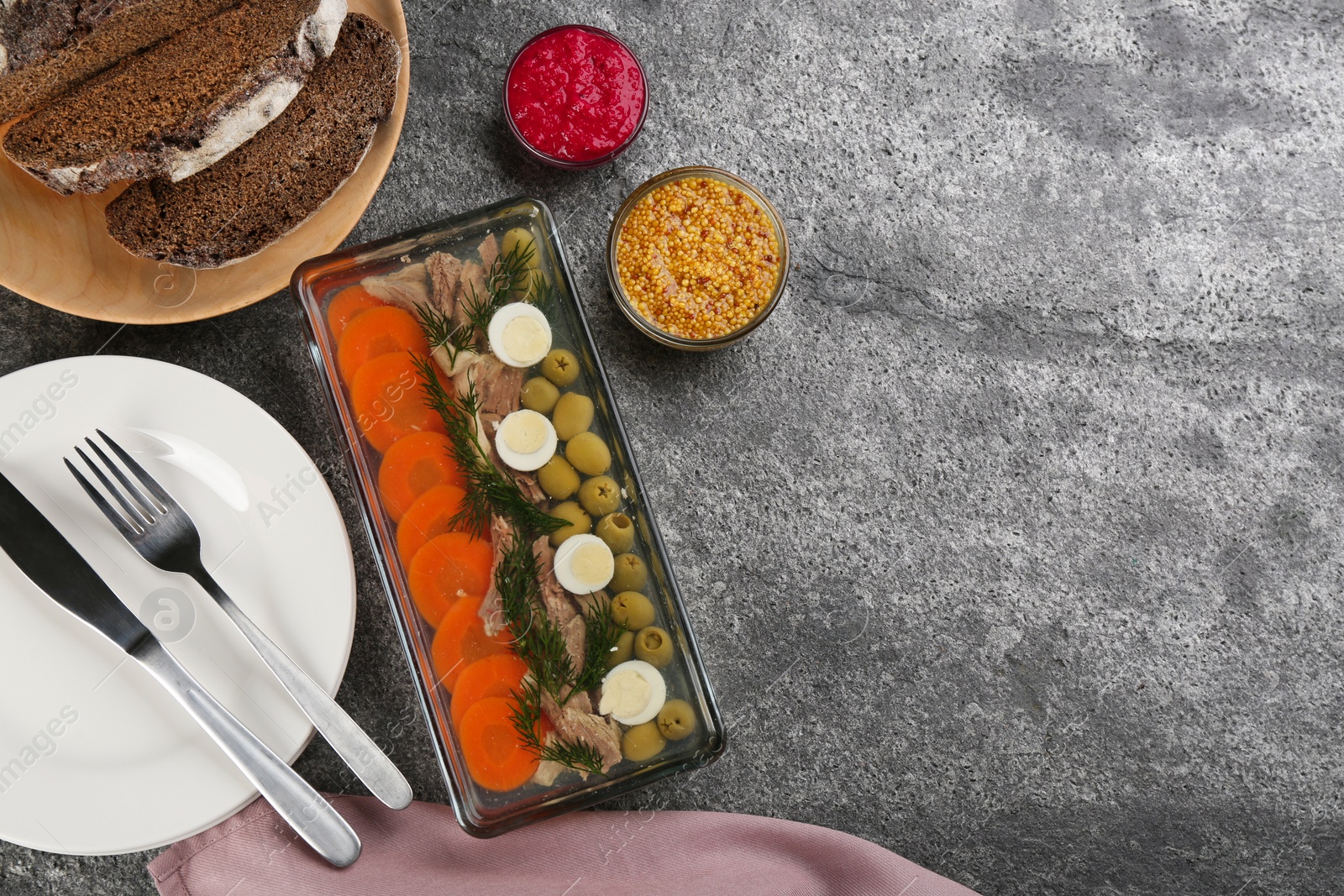 Photo of Delicious aspic with meat and vegetables served on grey table, flat lay. Space for text