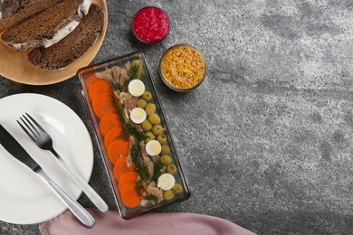 Delicious aspic with meat and vegetables served on grey table, flat lay. Space for text