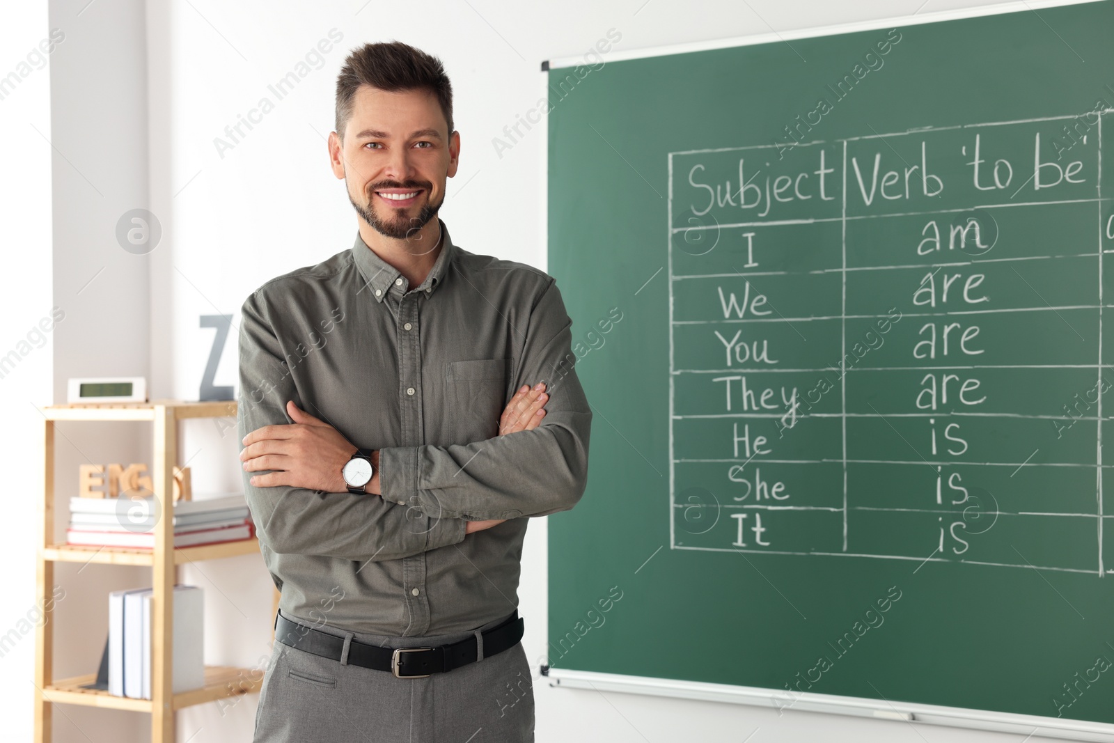 Photo of Happy teacher at blackboard in classroom during English lesson
