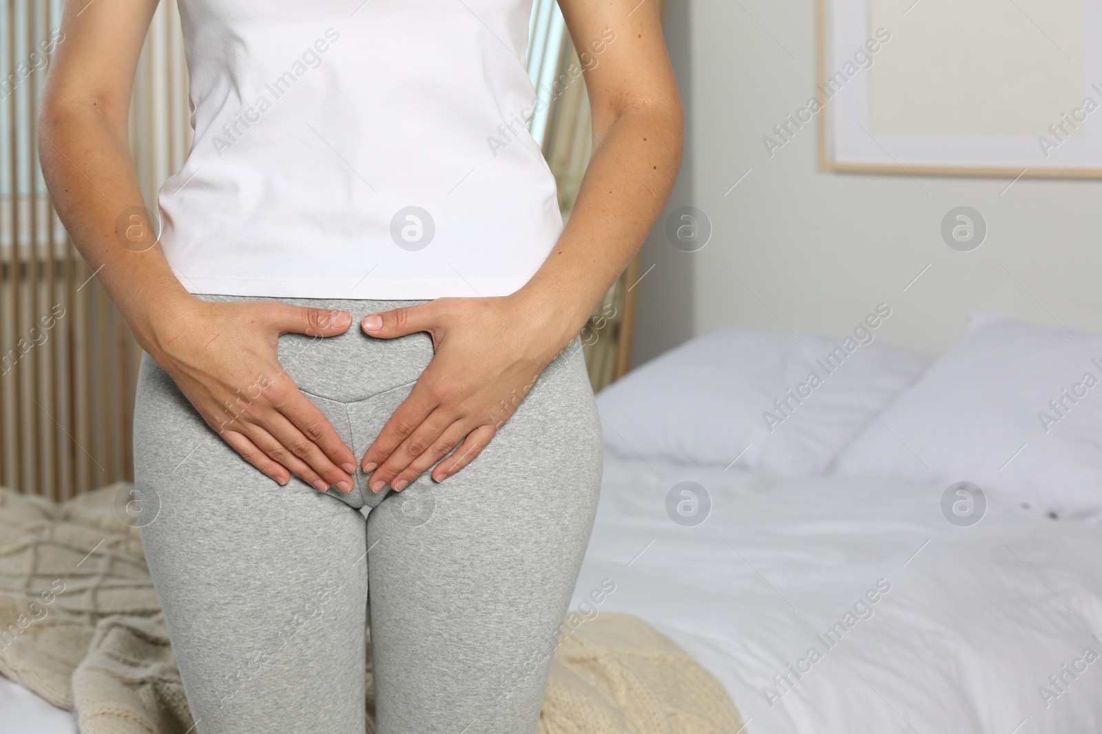 Photo of Woman suffering from genital herpes in bedroom, closeup. Space for text