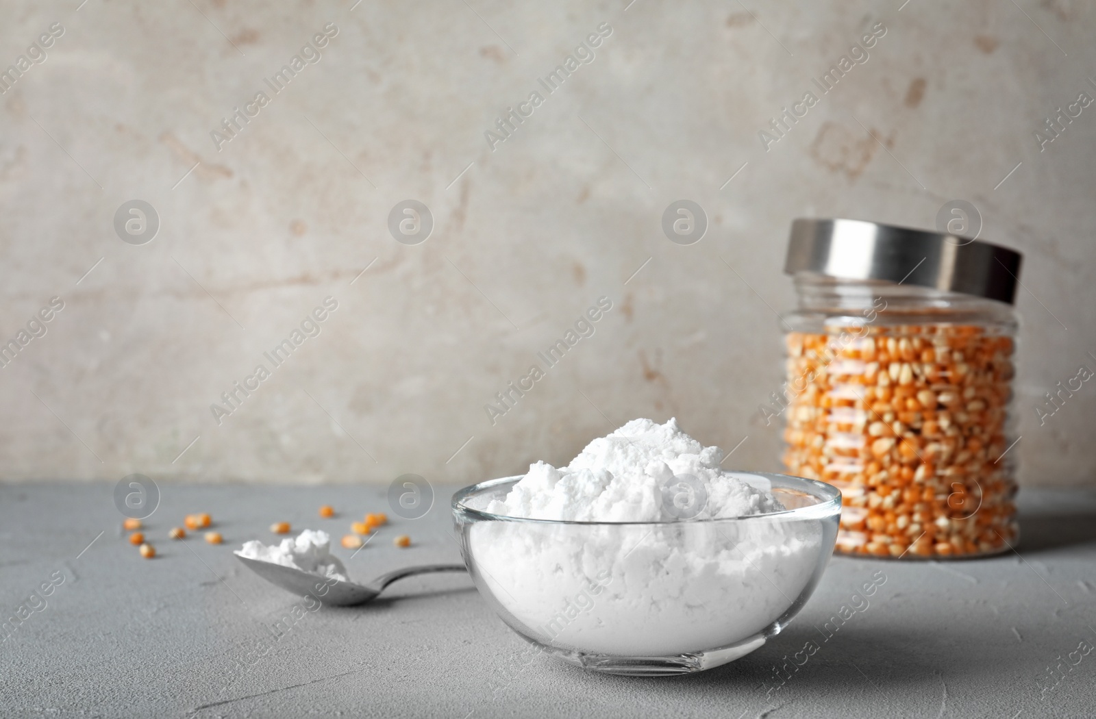 Photo of Bowl and spoon with corn starch on grey table. Space for text