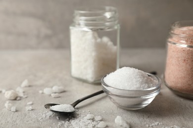 Photo of Different natural salt on grey textured table, closeup