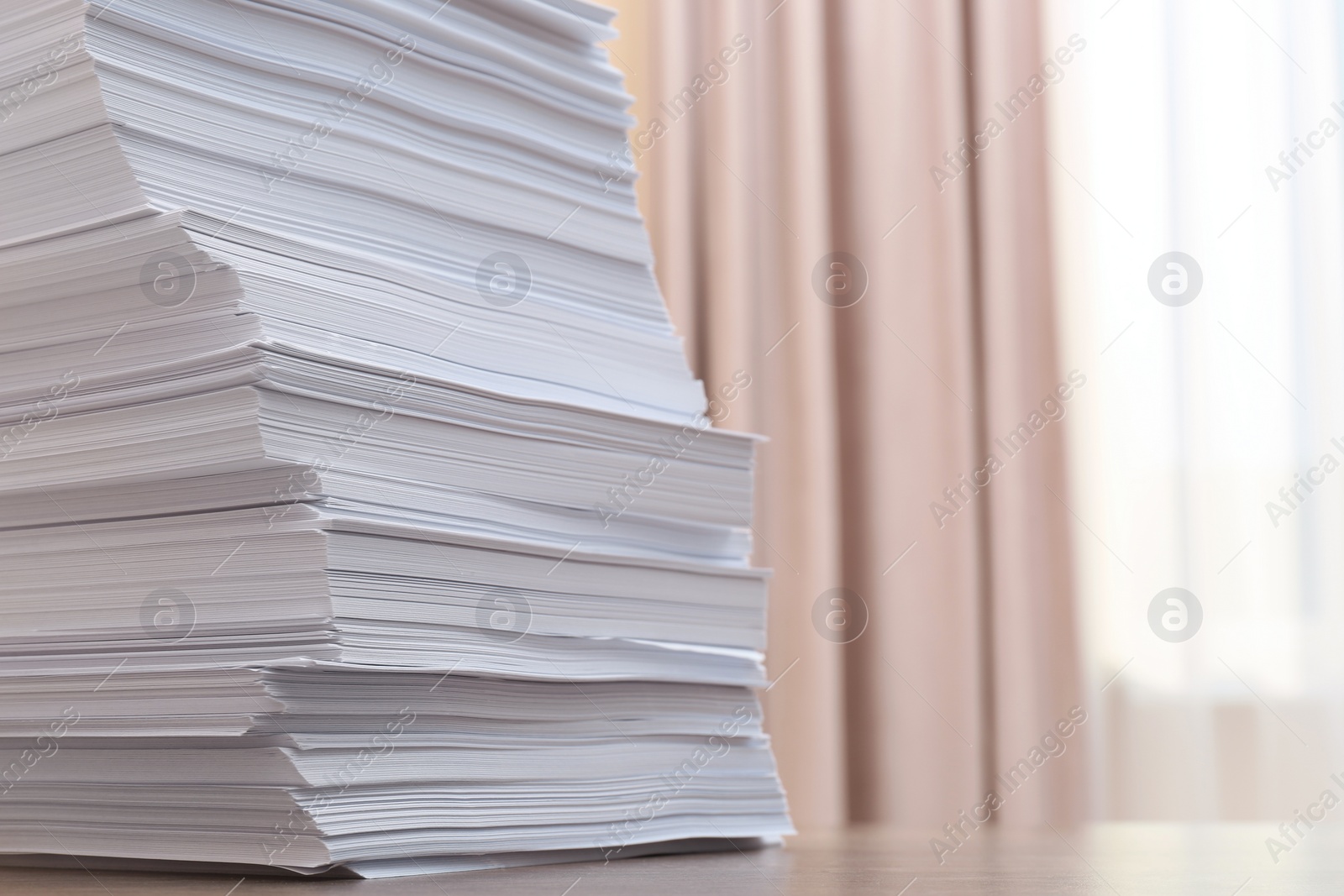 Photo of Stack of paper sheets on wooden table indoors, closeup. Space for text