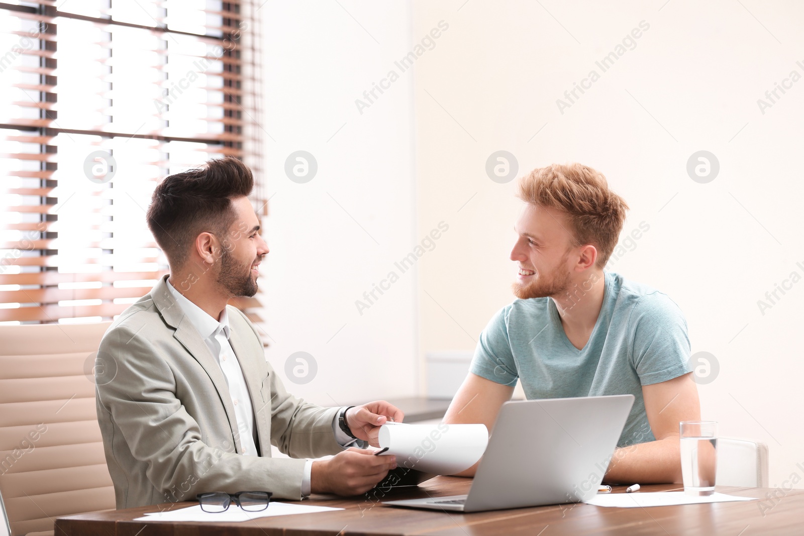 Photo of Insurance agent consulting young man in office