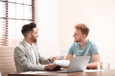 Photo of Insurance agent consulting young man in office