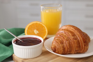 Photo of Breakfast time. Fresh croissant, jam and orange juice on table, closeup