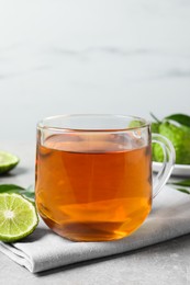 Photo of Glass cup of tasty bergamot tea and fresh fruit on light grey table