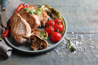 Photo of Delicious grilled meat and vegetables served on wooden table, space for text