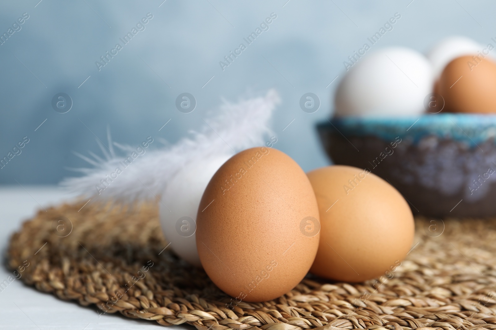 Photo of Fresh raw chicken eggs on wicker mat