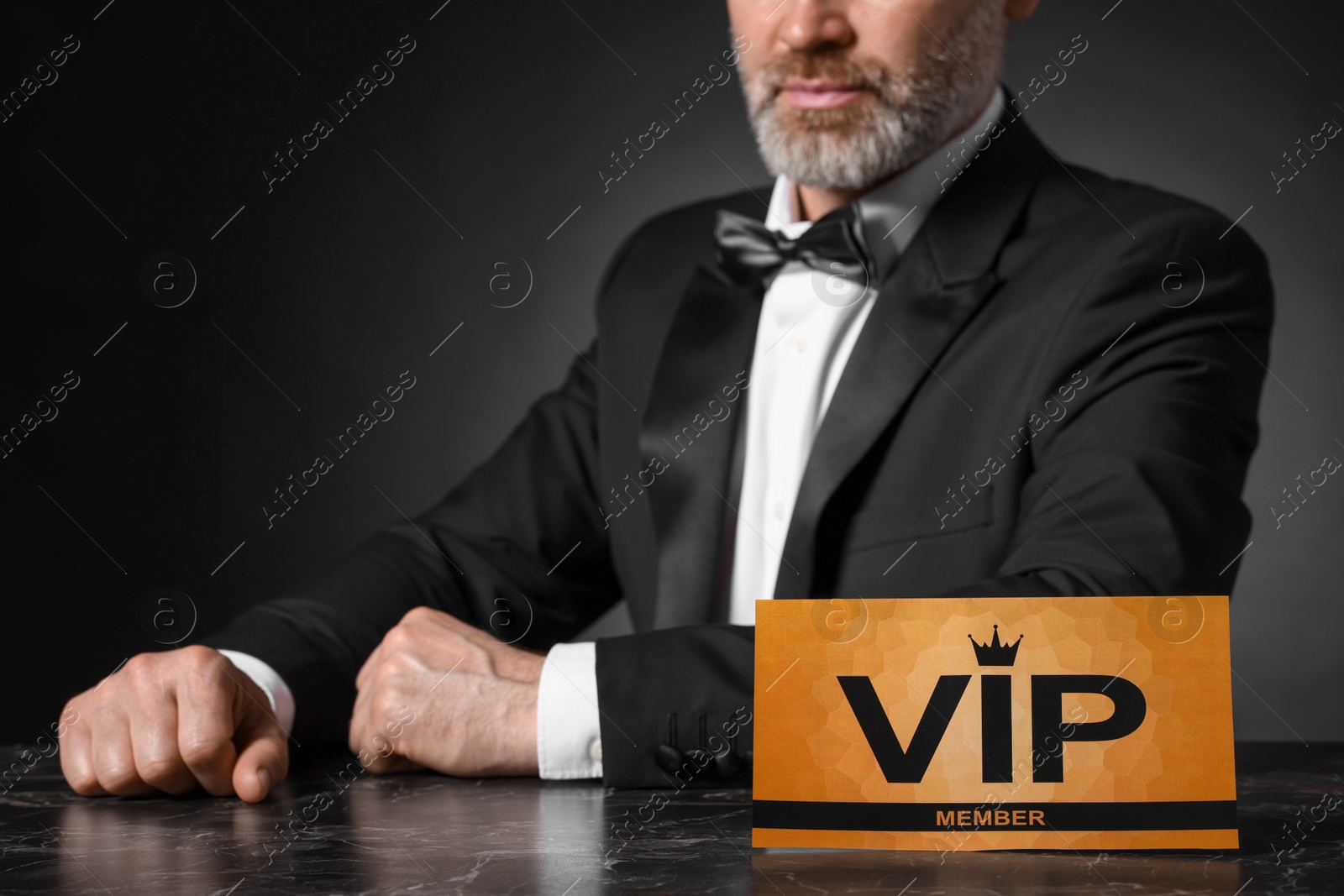 Photo of Man sitting at table with VIP sign on black background, closeup