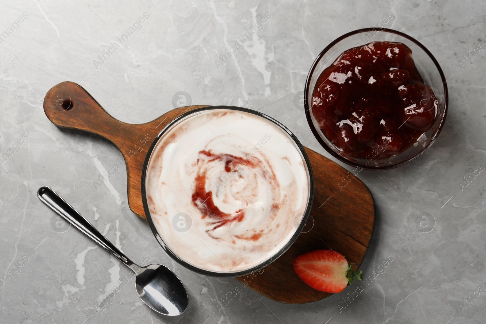 Photo of Tasty yoghurt with jam and strawberry on grey table, flat lay