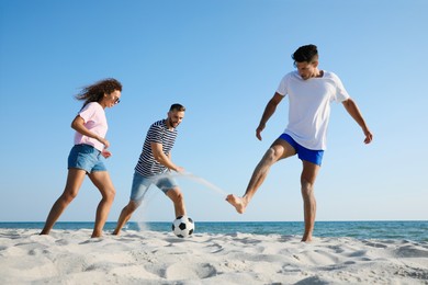 Group of friends playing football on beach