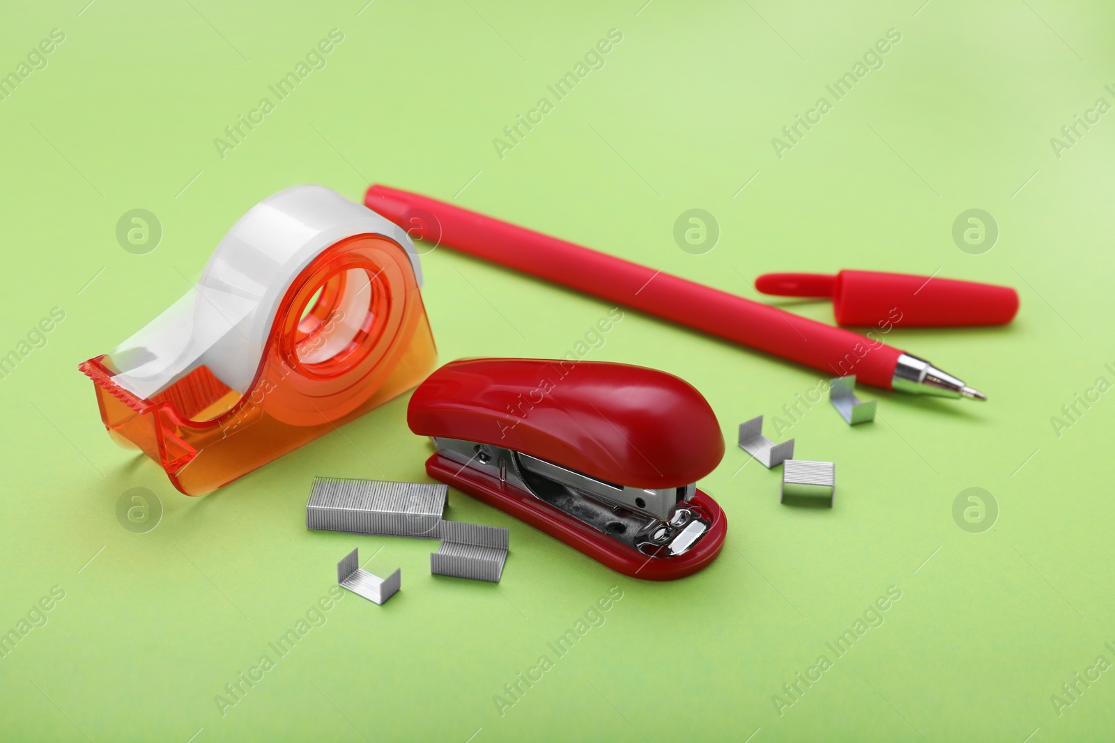 Photo of New bright stapler with stationery on green background