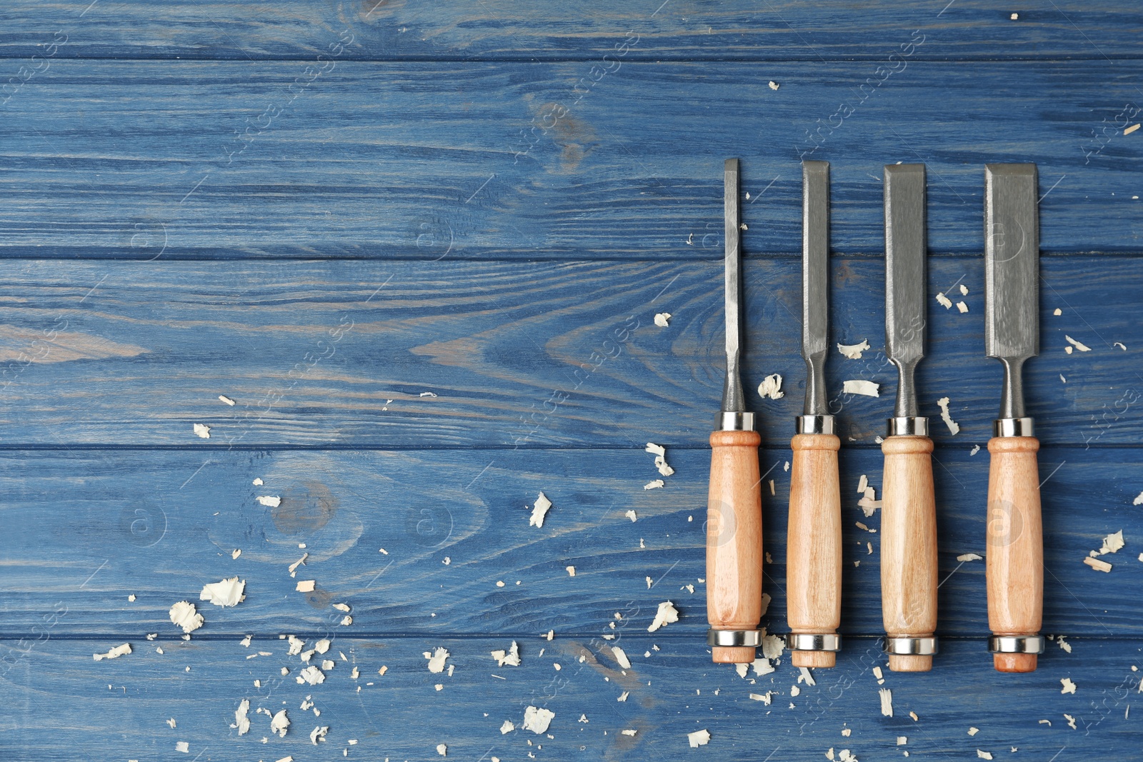 Photo of Modern chisels on blue wooden background, flat lay with space for text. Carpenter's tools