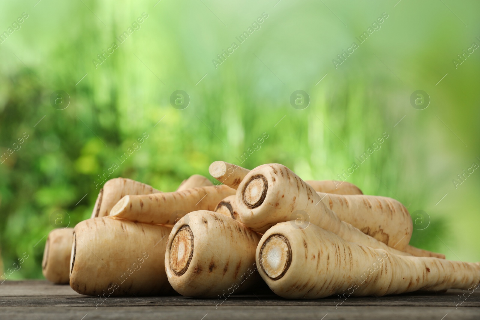 Photo of Delicious fresh ripe parsnips on wooden table outdoors
