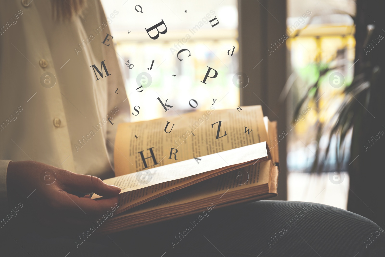 Image of Woman reading book with letters flying over it indoors, closeup