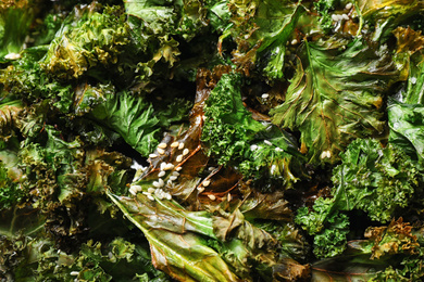 Photo of Tasty baked kale chips as background, closeup