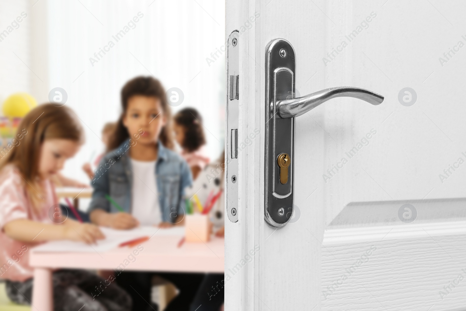 Image of Wooden door open into modern classroom with children