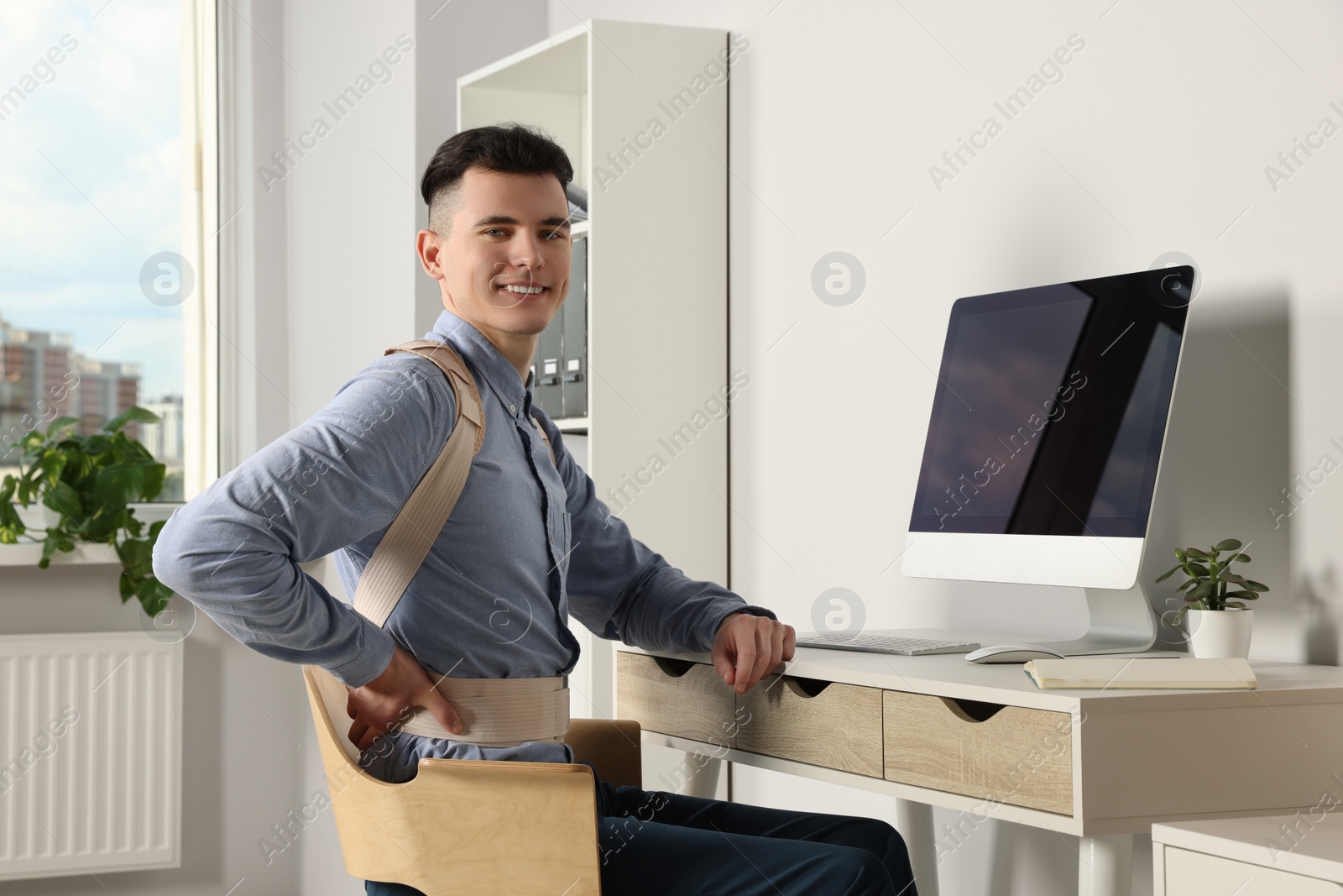 Photo of Man with orthopedic corset working on computer in room