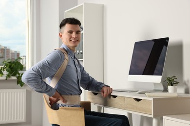 Man with orthopedic corset working on computer in room