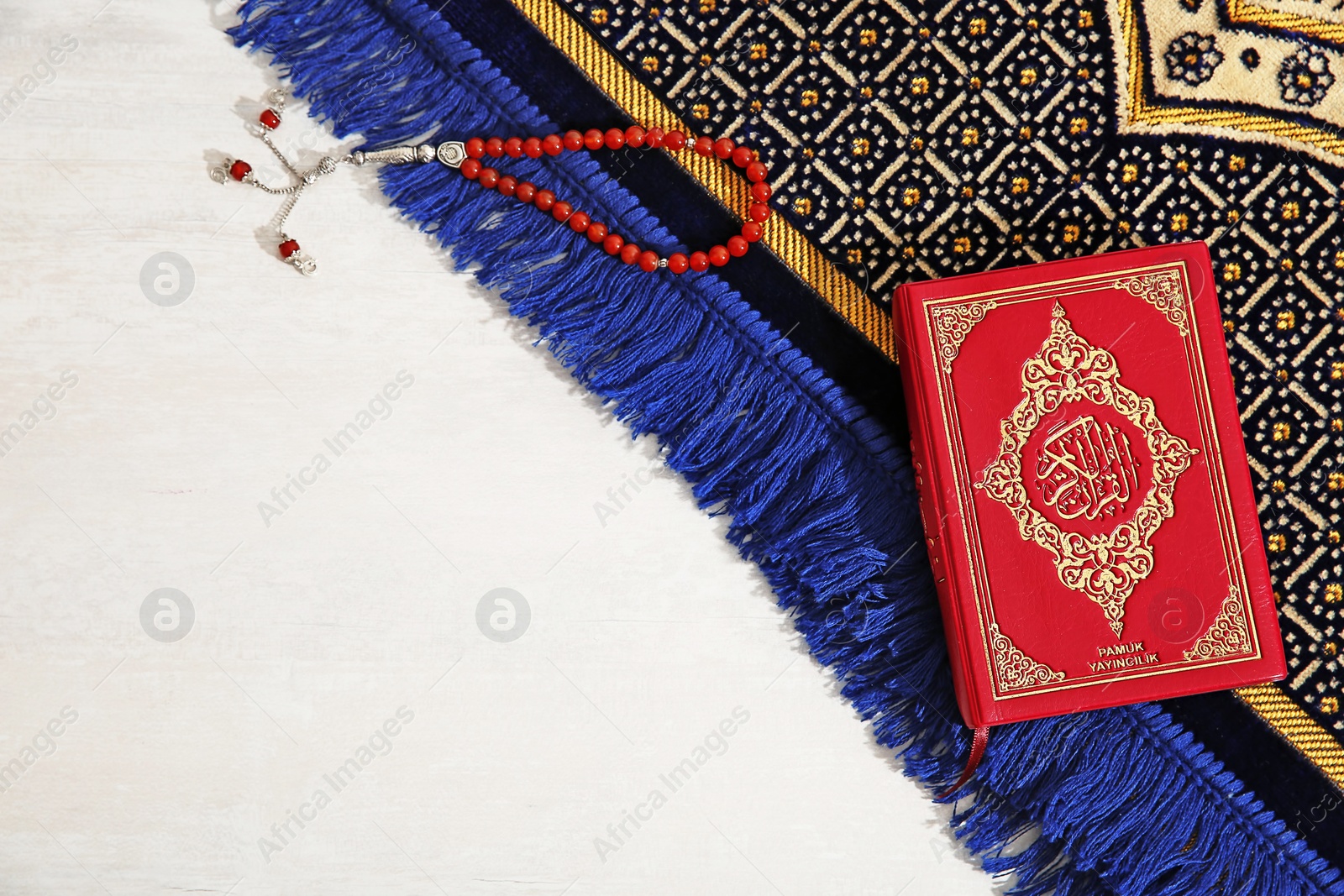 Photo of Muslim prayer beads, Quran, rug and space for text on light background, top view