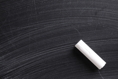 Photo of Piece of white chalk on blackboard, top view. Space for text