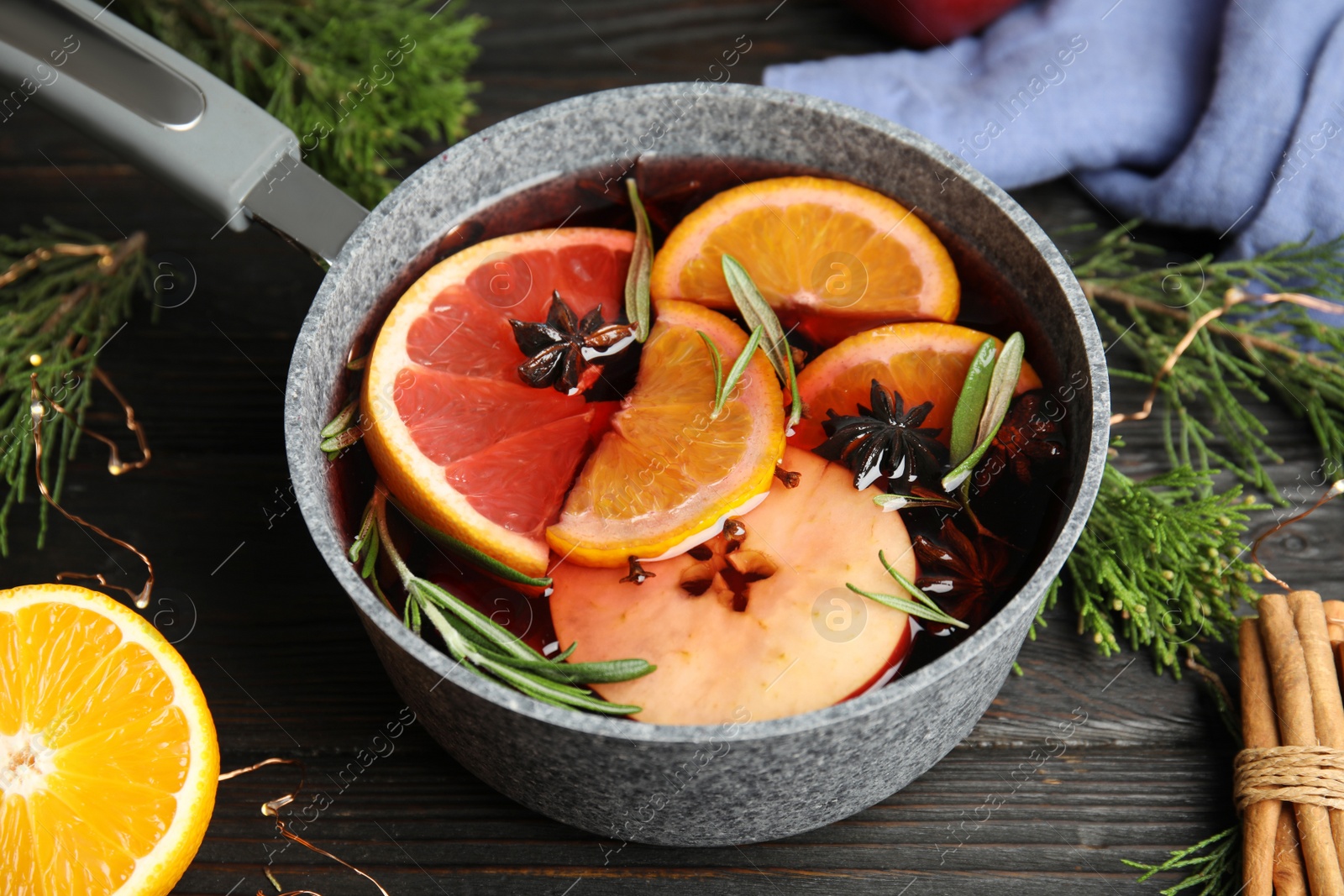 Photo of Tasty mulled wine with spices in cooking pot on wooden table