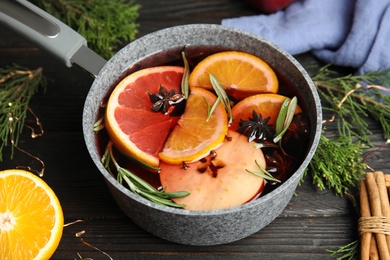 Photo of Tasty mulled wine with spices in cooking pot on wooden table