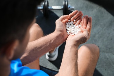 Sportsman with handful of pills in gym, closeup. Doping concept