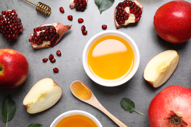 Honey, apples and pomegranates on grey table, flat lay. Rosh Hashanah holiday