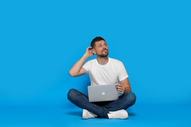Photo of Pensive man sitting with laptop on light blue background