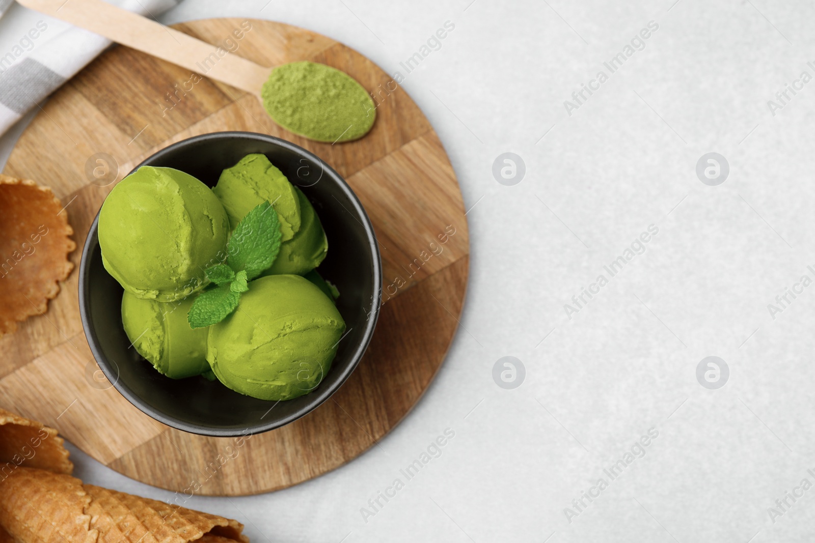Photo of Tasty matcha ice cream in bowl on light table, flat lay. Space for text