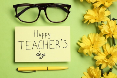 Flat lay composition with words HAPPY TEACHER'S DAY and flowers on light green background